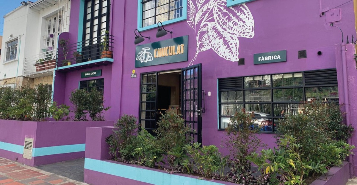 Fachada morada y turquesa de Chuculat en Chapinero con mural de mazorca de cacao